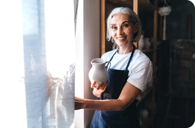 Smiling Female Holding Clay Pottery in Her Art Studio
